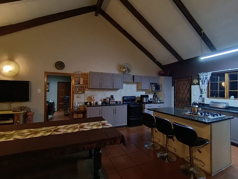 Spacious open-plan kitchen and living area featuring vaulted ceilings with exposed timber beams, granite countertops, and a central kitchen island.