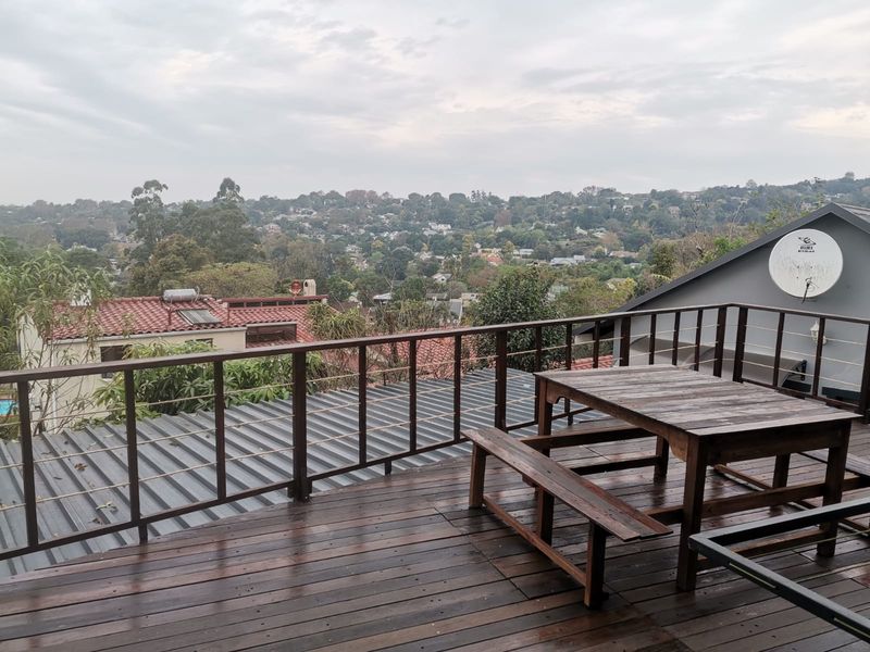 An elevated timber deck balcony featuring a wooden balustrade and expansive views over the surrounding residential neighbourhood.