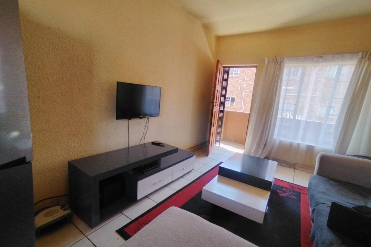 A living room featuring tiled flooring, textured walls, and direct access to an outdoor balcony area.