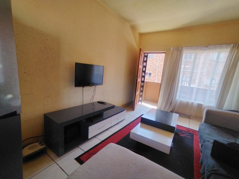 A living room featuring tiled flooring, textured walls, and direct access to an outdoor balcony area.