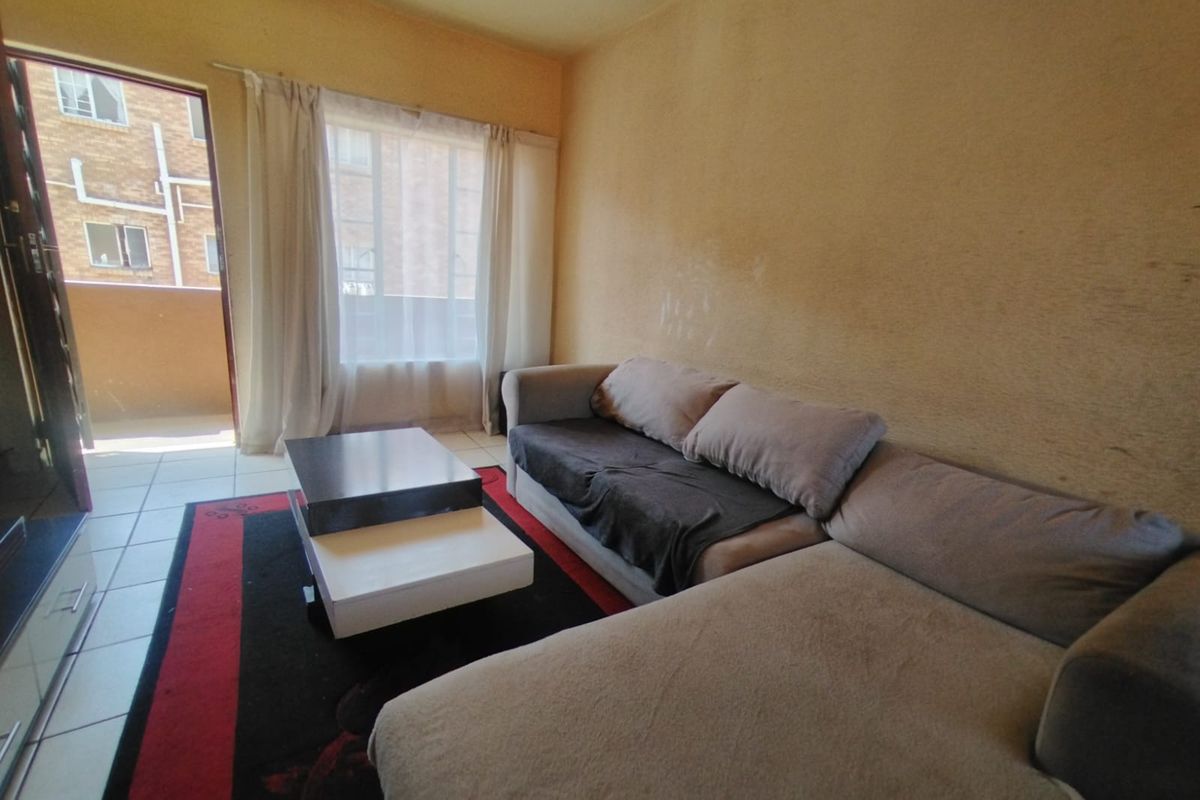 A living room area featuring tiled flooring and a sliding glass door leading to an outdoor space, with walls showing signs of wear.
