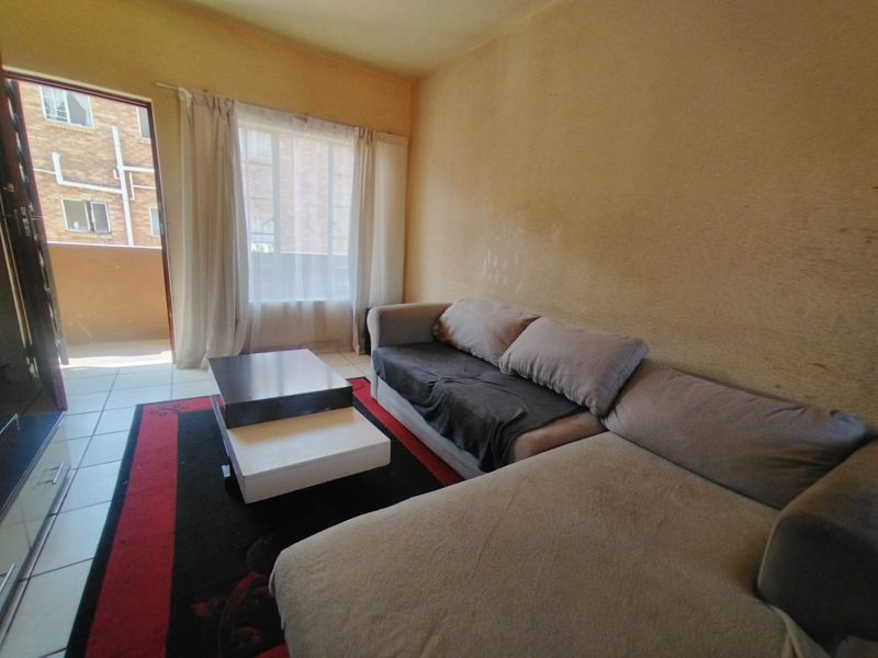 A living room area featuring tiled flooring and a sliding glass door leading to an outdoor space, with walls showing signs of wear.