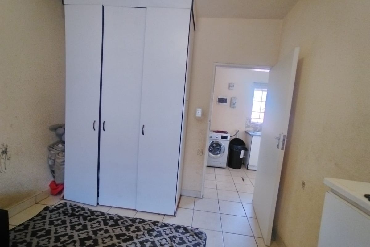 Bedroom featuring a built-in wardrobe and tiled flooring, with an adjacent view into a laundry area.