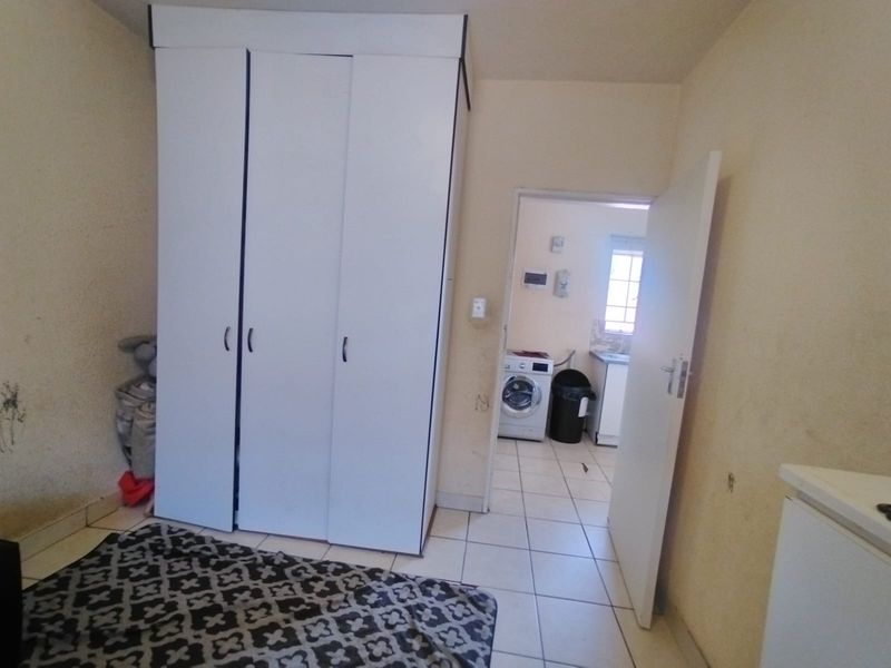 Bedroom featuring a built-in wardrobe and tiled flooring, with an adjacent view into a laundry area.