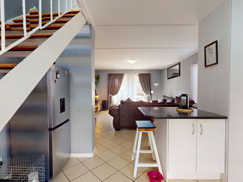 Open plan living area featuring a breakfast bar, tiled flooring, and an internal staircase leading to the upper level.