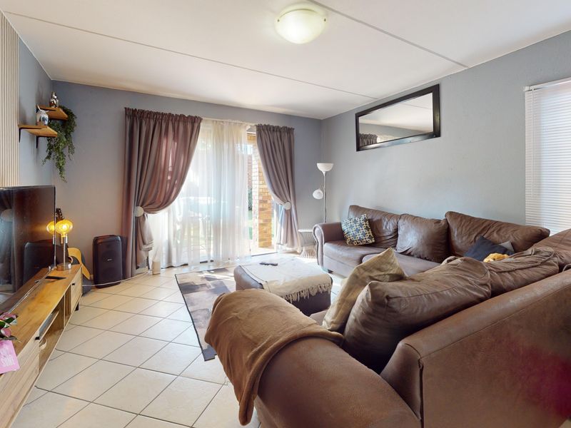 A comfortable living room featuring tiled flooring and a sliding glass door providing access to the outdoor area.