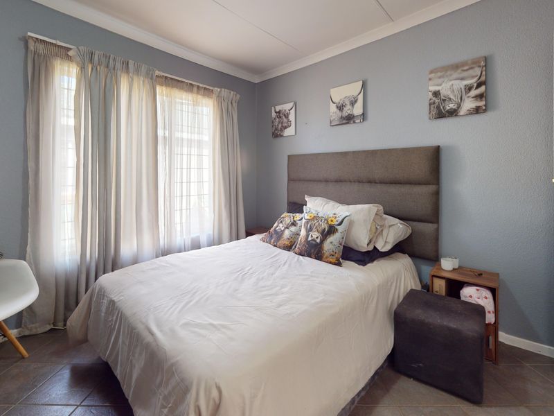 A well-lit bedroom featuring tiled flooring, neutral wall tones, and a coved ceiling, providing a comfortable and functional living space.