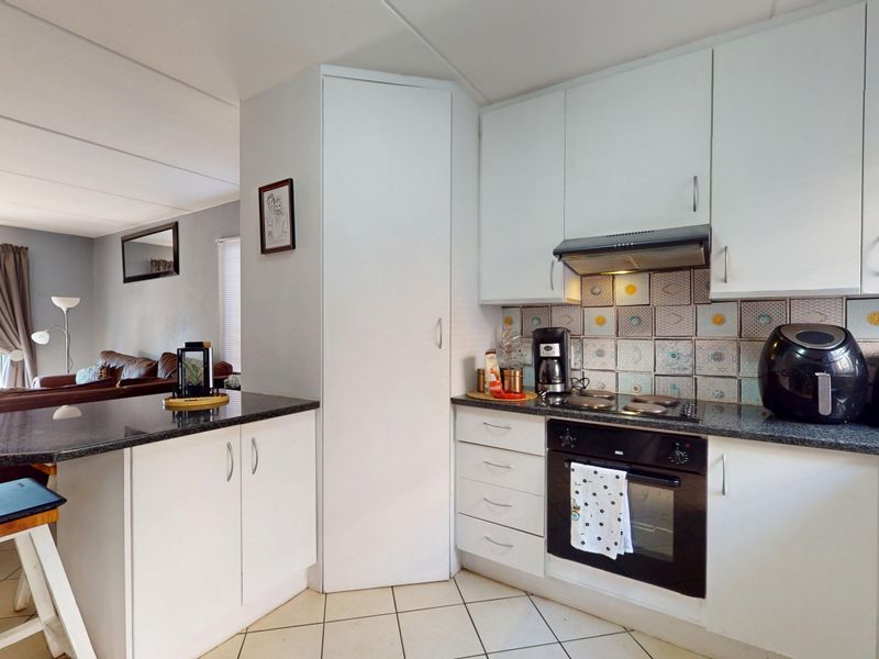 Open-plan kitchen featuring white cabinetry, granite countertops, and integrated appliances, seamlessly flowing into the adjacent living area.