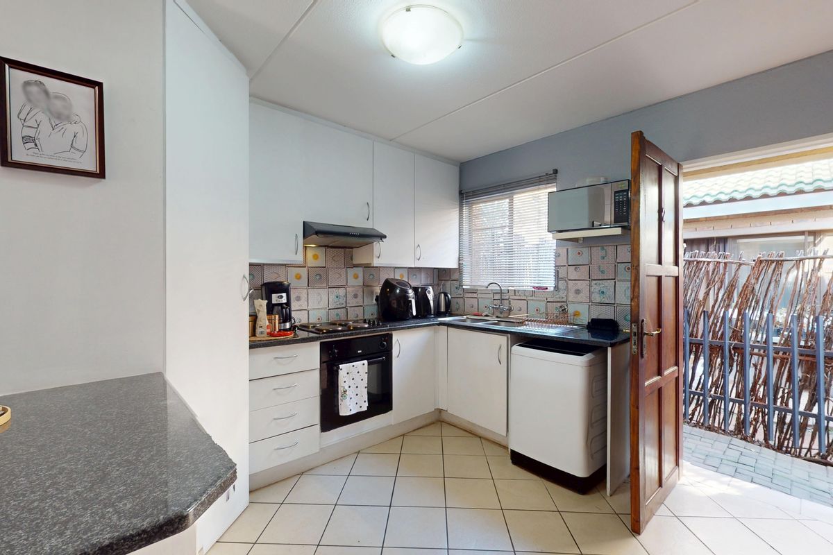 Compact kitchen featuring white cabinetry, built-in oven and hob, tiled backsplash, and direct access to an outdoor area.