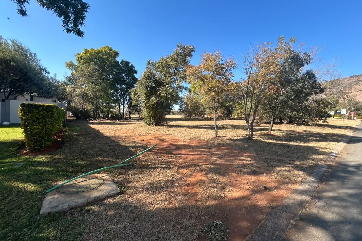A vacant residential plot featuring established trees and natural landscaping, offering a clear space for future development.