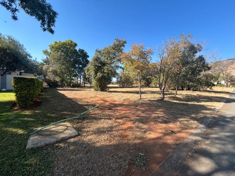 A vacant residential plot featuring established trees and natural landscaping, offering a clear space for future development.