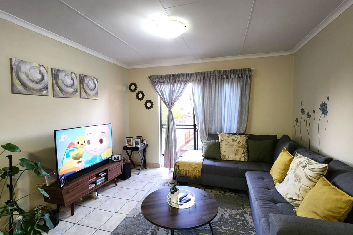 A comfortable living room featuring tiled flooring and direct access to a balcony through a sliding glass door.