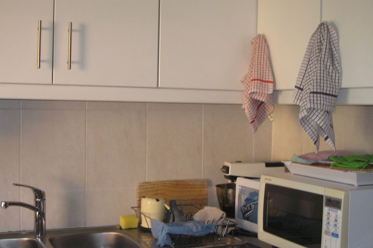 A functional kitchen area featuring a stainless steel double sink, tiled splashback, and ample built-in cabinetry with granite countertops.