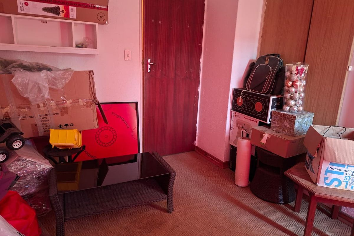 A bedroom space featuring built-in cupboards and a timber door, currently used for storage with carpeted flooring.