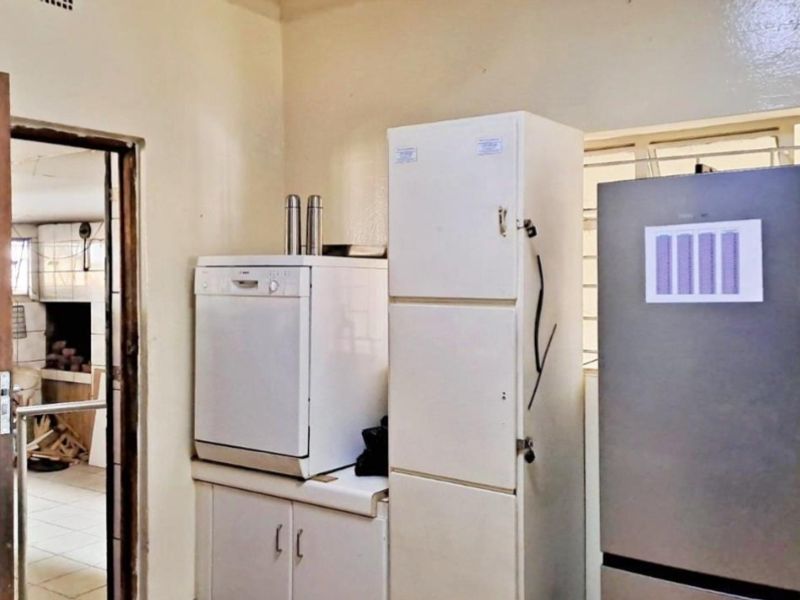 A functional scullery or utility area featuring built-in cabinetry and security bars on the window, providing practical storage and workspace.