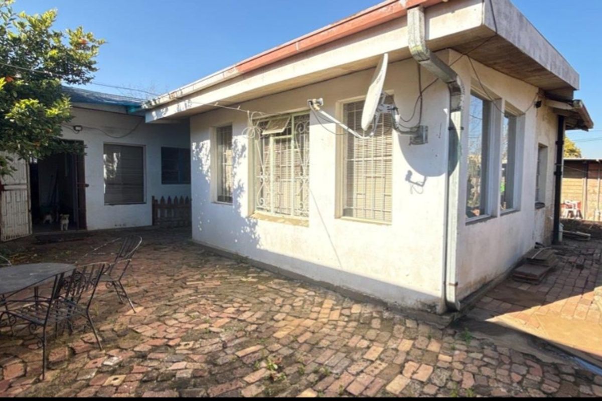 Rear exterior view of the house featuring brick paving, security bars on windows, and guttering systems.
