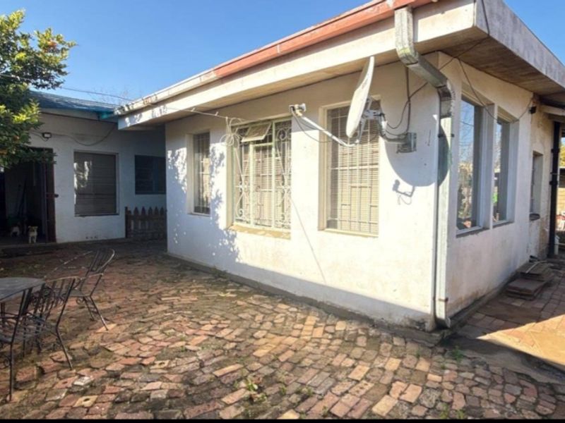 Rear exterior view of the house featuring brick paving, security bars on windows, and guttering systems.