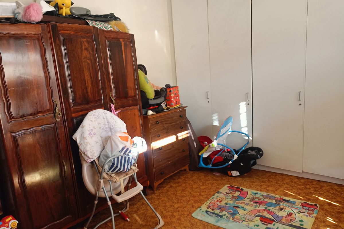 A bedroom featuring built-in white wardrobes and patterned flooring, offering potential for modernization and improved layout.