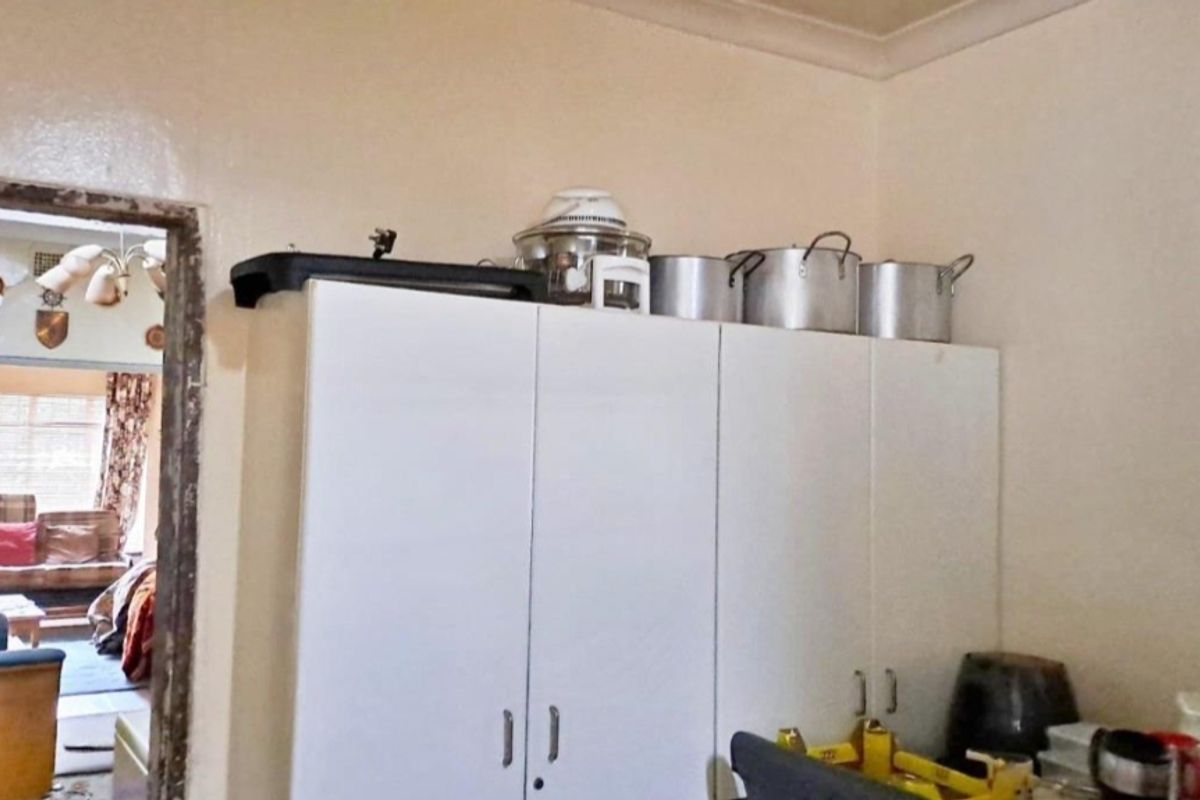 A kitchen area featuring white built-in cabinetry with visible wear on the surrounding door frame and wall finishes.