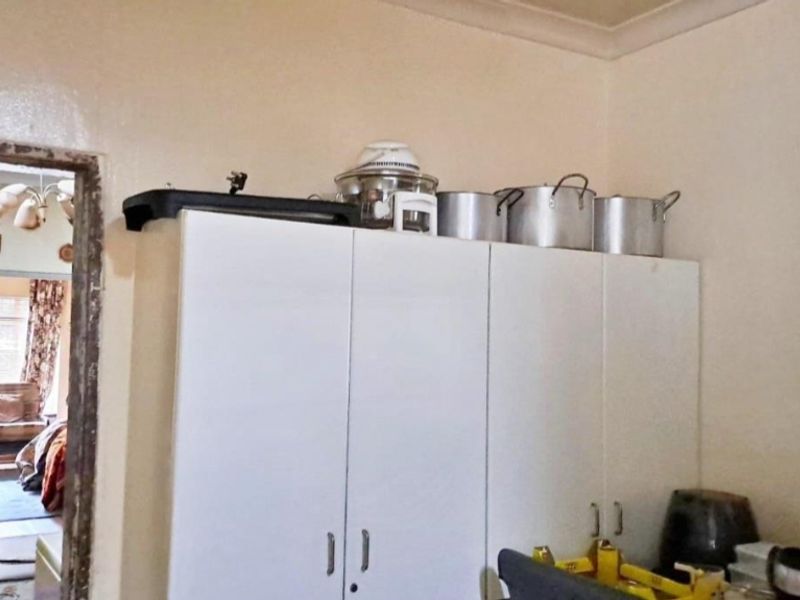 A kitchen area featuring white built-in cabinetry with visible wear on the surrounding door frame and wall finishes.