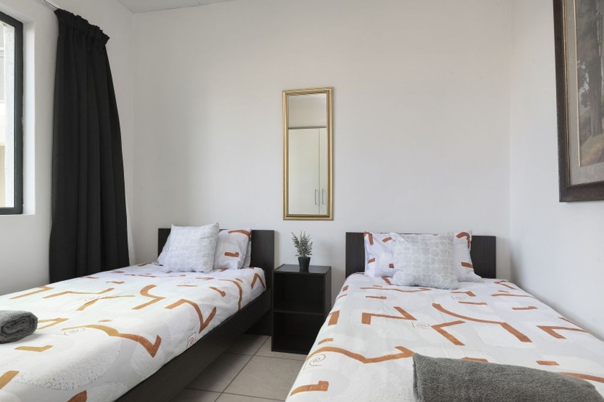 A functional bedroom featuring tiled flooring and neutral wall finishes, providing a clean and simple space.