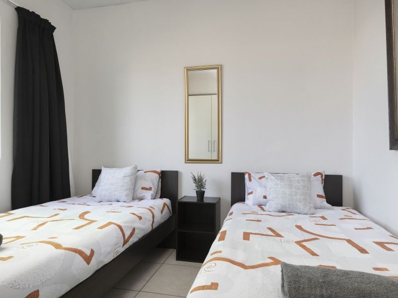 A functional bedroom featuring tiled flooring and neutral wall finishes, providing a clean and simple space.