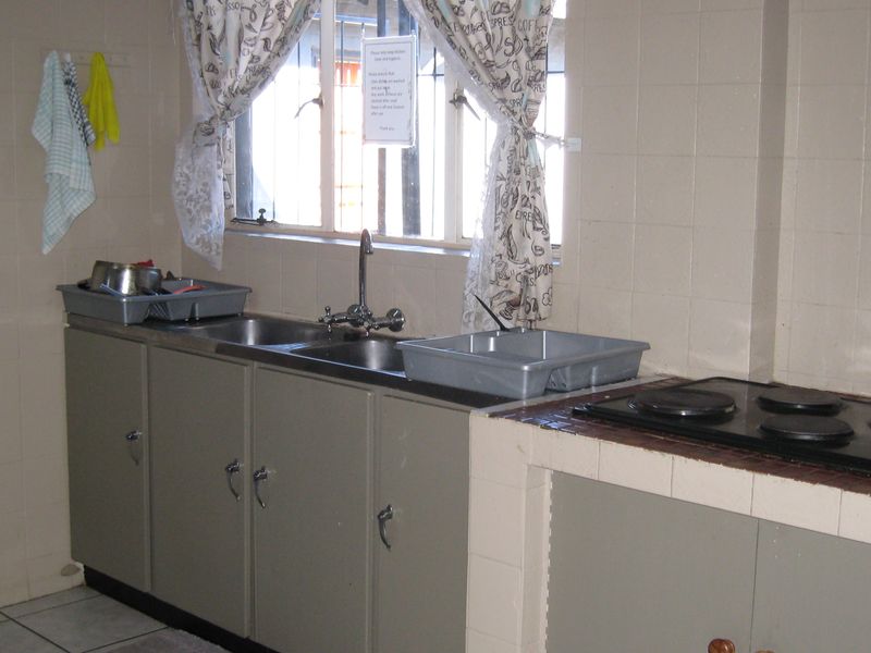 A functional kitchen area featuring built-in cabinetry, a double sink, and an integrated electric hob with tiled splashbacks.