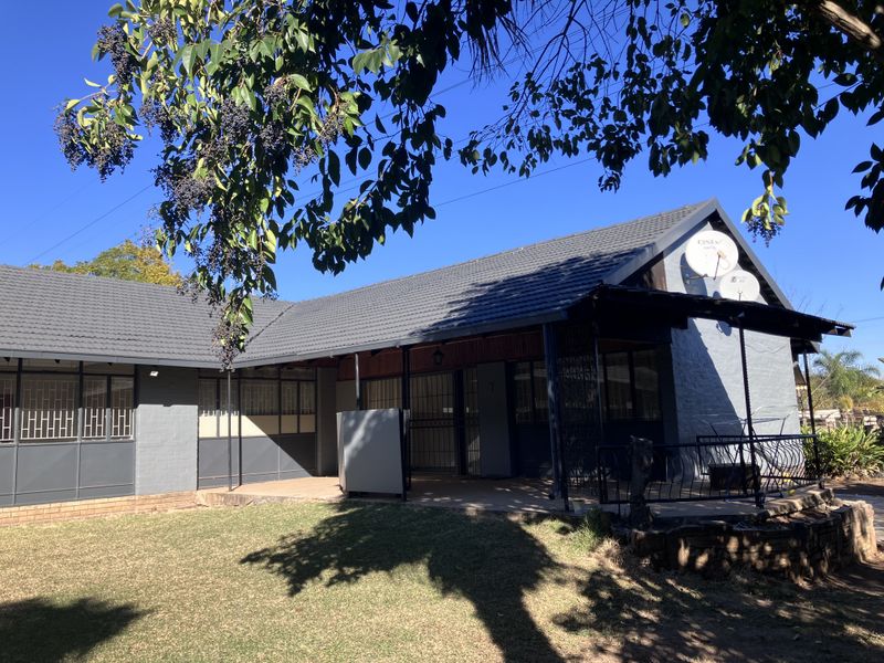 A view of the rear exterior of the house featuring a tiled roof, covered patio area, and secure metal window frames.