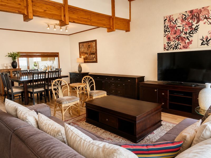 Spacious open-plan living and dining area featuring exposed timber ceiling beams, laminate flooring, and a convenient kitchen pass-through window.