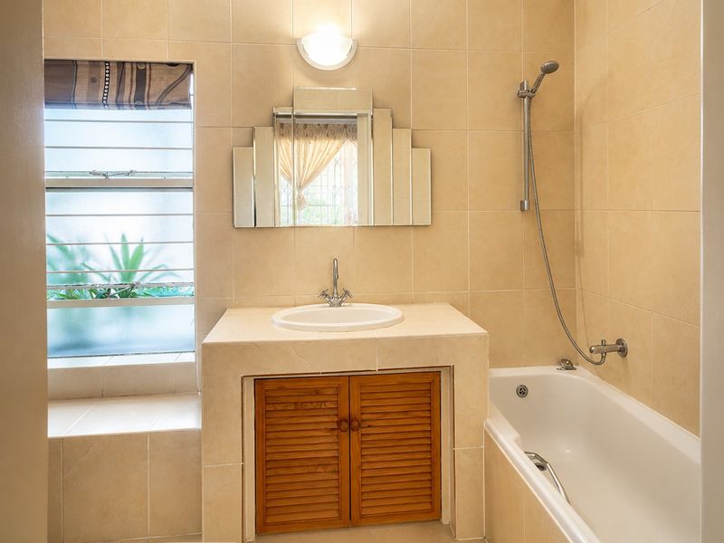 A functional bathroom featuring a tiled vanity with built-in cabinetry, a drop-in basin, and a bathtub with a handheld shower attachment.