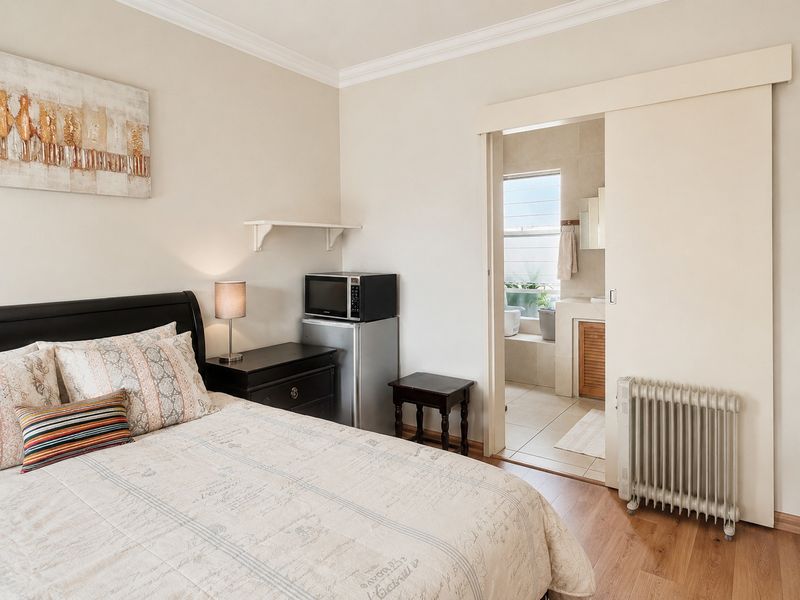 A well-maintained bedroom featuring laminate flooring, coving, and direct access to an en-suite bathroom through a sliding door.