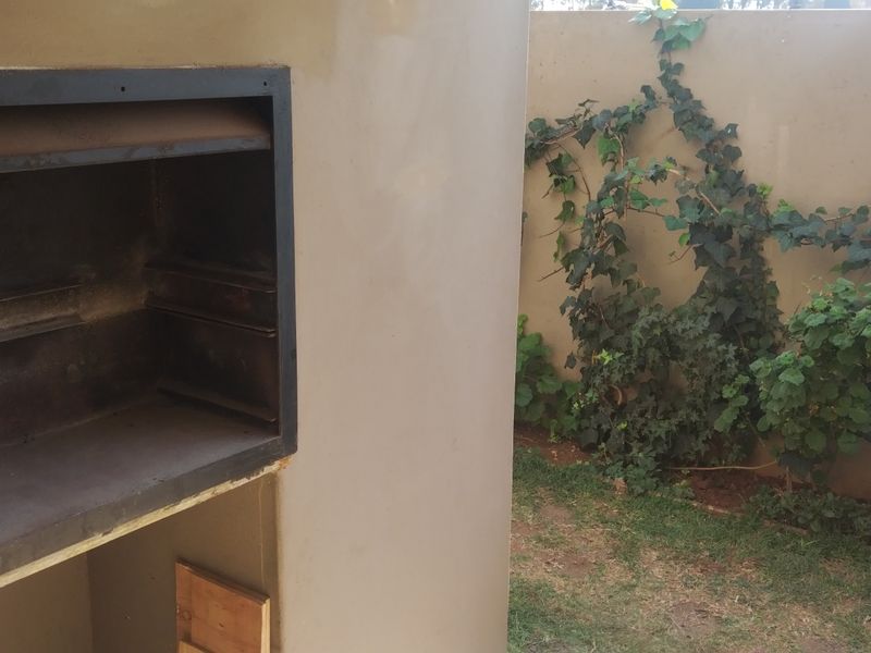 Outdoor patio area featuring a built-in braai unit set against a boundary wall with climbing vegetation.