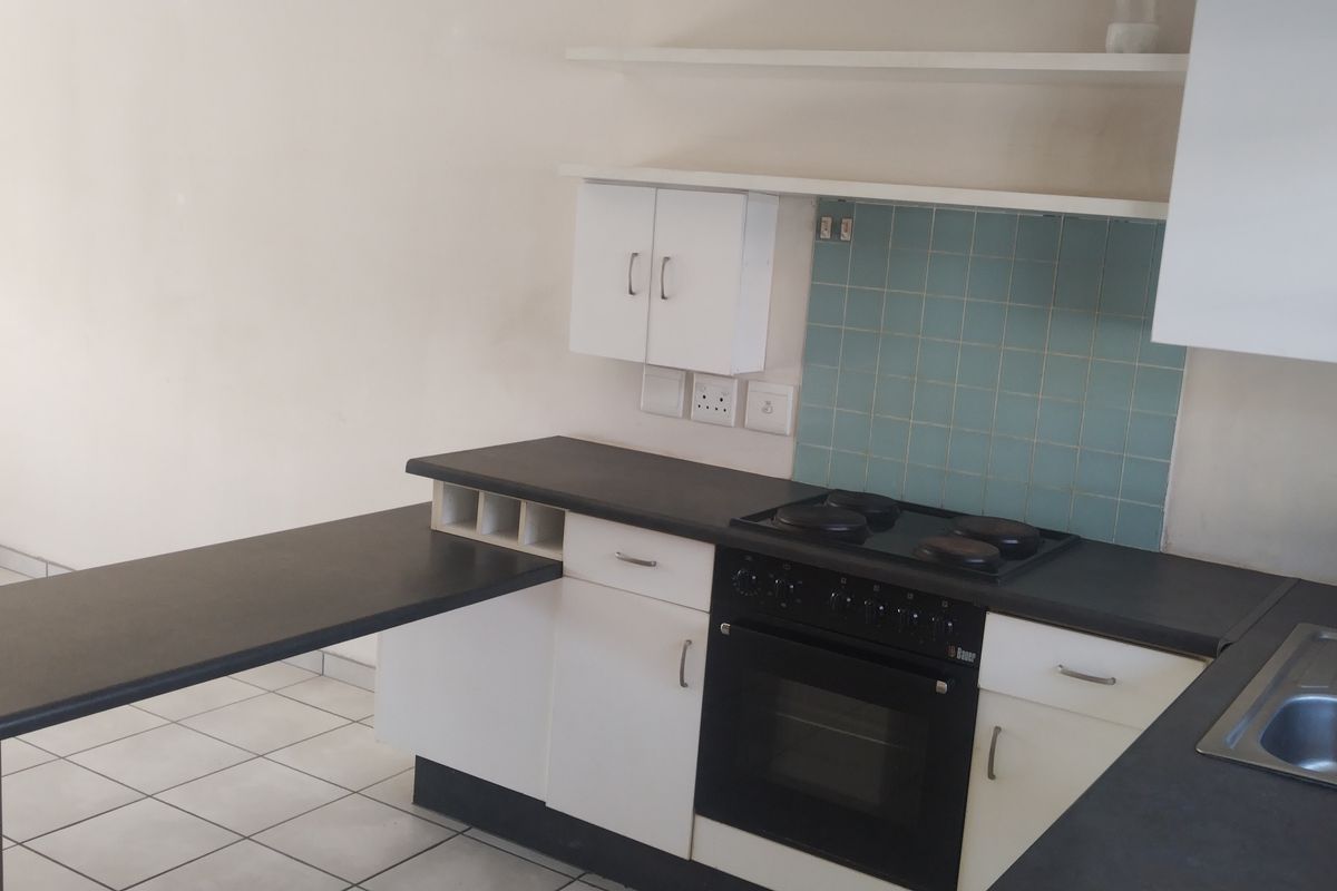 A functional kitchen featuring white cabinetry, dark laminate countertops, an integrated electric stove and oven, and a tiled backsplash.
