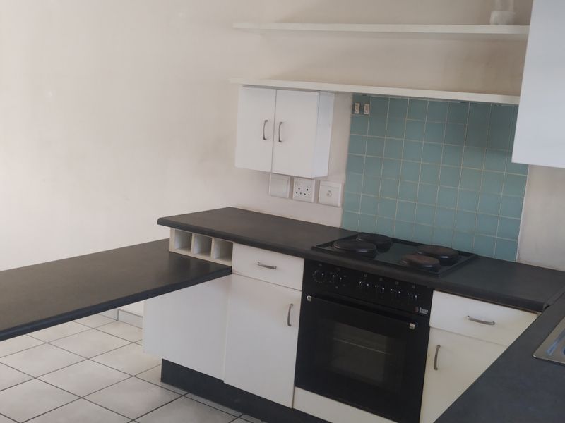 A functional kitchen featuring white cabinetry, dark laminate countertops, an integrated electric stove and oven, and a tiled backsplash.