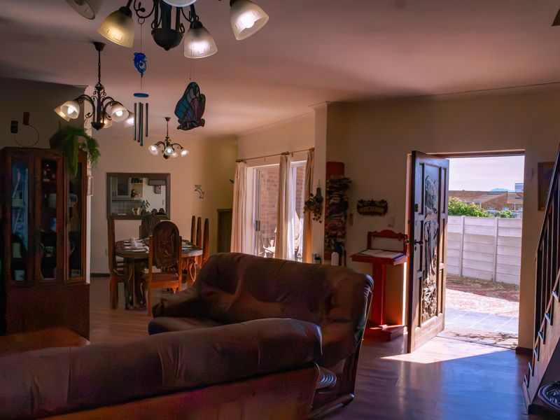 Open plan living and dining area featuring laminate flooring, sliding glass doors to the exterior, and a decorative timber entrance door.