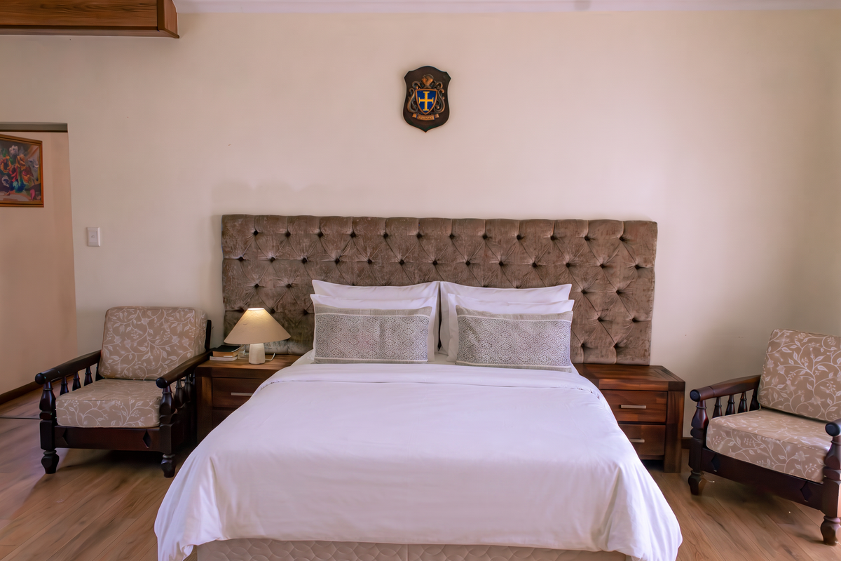 A well-maintained bedroom featuring laminate flooring and a large, tufted upholstered headboard.