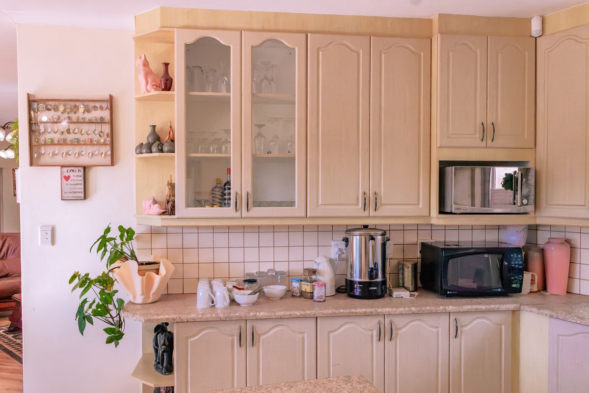 A functional kitchen area featuring light-toned built-in cabinetry, laminate countertops, and a classic ceramic tile backsplash with integrated microwave housing.