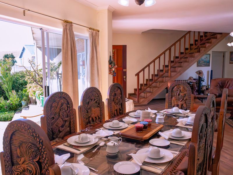 Open plan dining area featuring a wooden staircase, laminate flooring, and large sliding glass doors providing direct access to the garden.