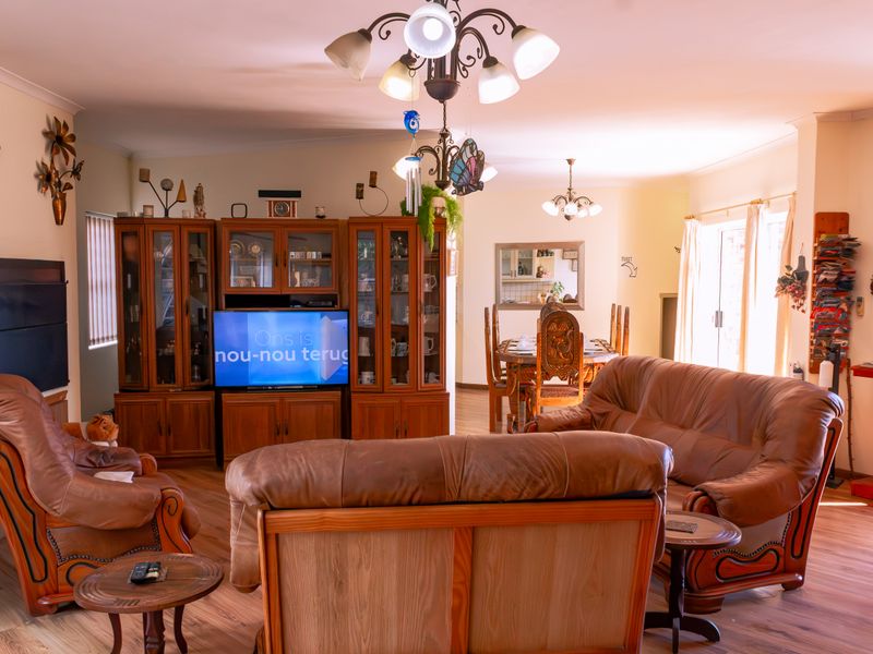 Spacious open-plan living and dining area featuring laminate flooring, built-in display cabinetry, and sliding glass doors providing natural light.