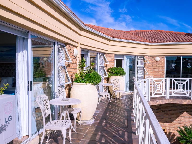 A spacious, tiled balcony featuring brick exterior walls, sliding glass doors, and white railings, providing a pleasant outdoor living area.