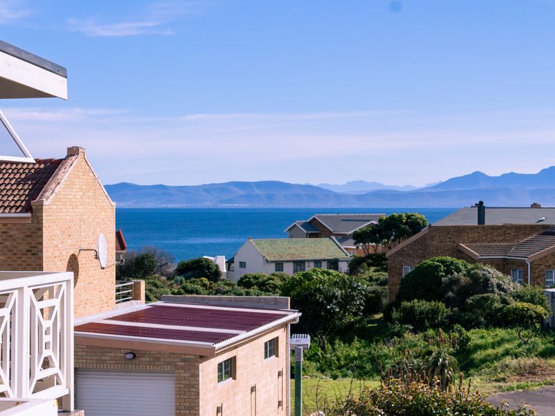 A scenic elevated view overlooking a coastal residential neighborhood with a clear outlook towards the ocean and distant mountain range.