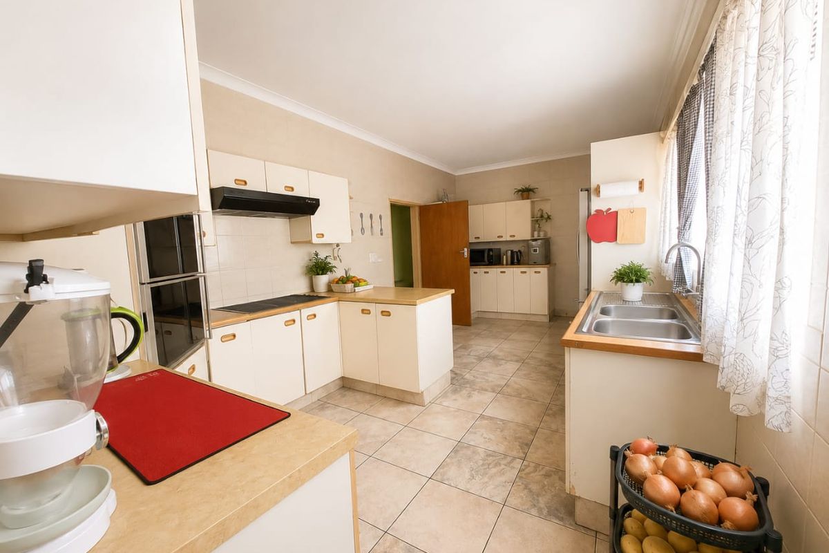 A functional kitchen featuring built-in cabinetry, laminate countertops, a double stainless steel sink, and integrated cooking appliances with tiled flooring throughout.