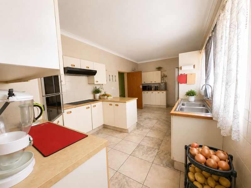A functional kitchen featuring built-in cabinetry, laminate countertops, a double stainless steel sink, and integrated cooking appliances with tiled flooring throughout.