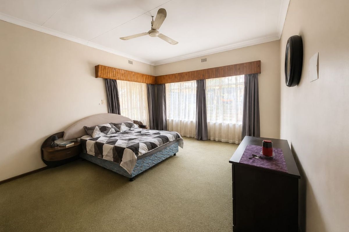 Spacious bedroom featuring carpeted flooring, a ceiling fan, and a built-in headboard with integrated side tables.