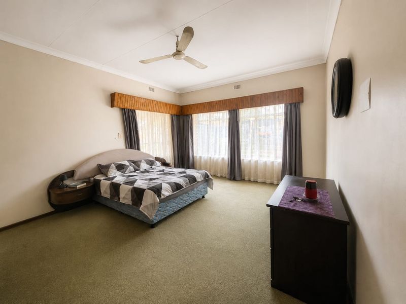 Spacious bedroom featuring carpeted flooring, a ceiling fan, and a built-in headboard with integrated side tables.