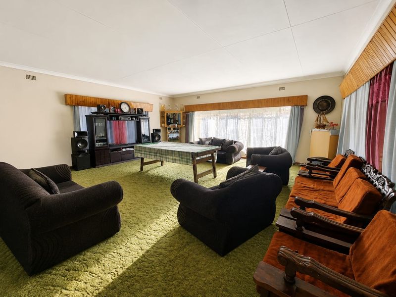Spacious living room featuring large windows, timber pelmets, and carpet flooring, offering a versatile area for relaxation and entertainment.