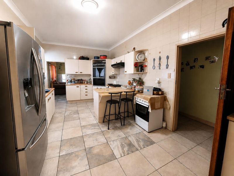 A functional kitchen featuring tiled flooring, built-in cabinetry, a breakfast counter, and integrated oven, offering a practical layout with potential for modern updates.