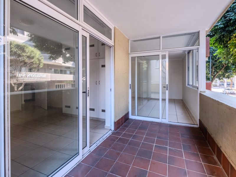 A spacious, tiled balcony featuring sliding glass doors and built-in storage cupboards, offering a versatile outdoor living space.