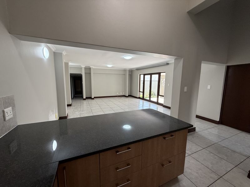 Spacious open-plan living area featuring tiled floors, a functional kitchen with granite countertops, and direct access to the outdoor space through sliding doors.