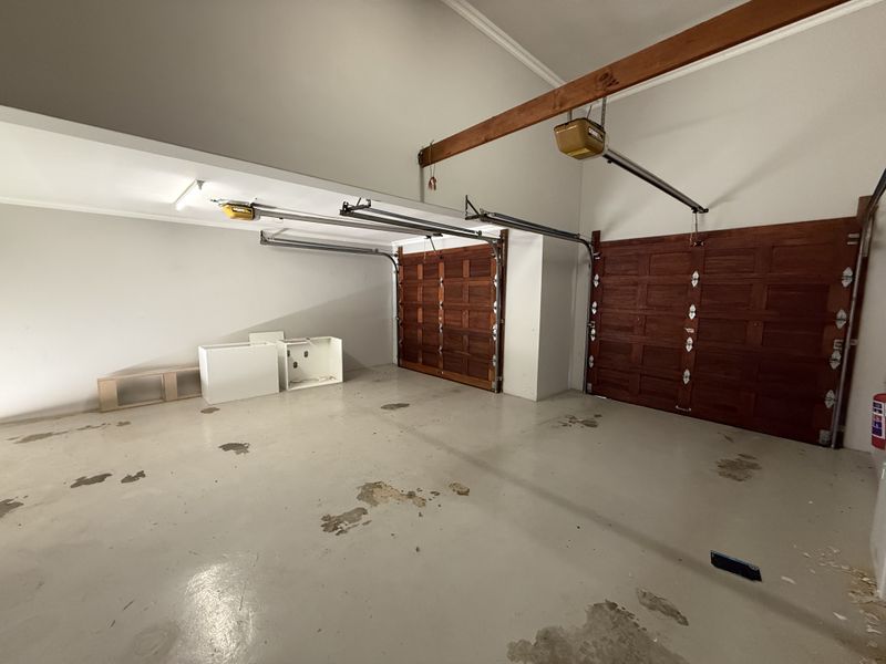Spacious double garage featuring timber sectional doors, automatic openers, and a painted concrete floor.